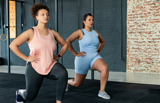 African American women performing forward lunges in gym with pull-up rig and smartwatches