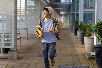 Beige sneakers pounding campus walkway under overhead beams, beside glass walls and potted plants