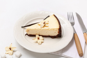 Plate with piece of sweet vanilla cheesecake on white background