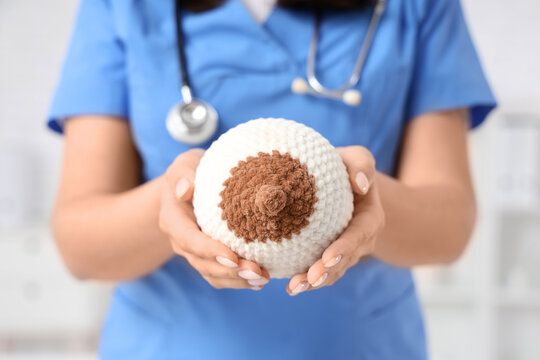 Female doctor with knitted breast model in clinic, closeup