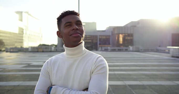 African American man spotting sun lowering, looking skyward and laughing on rooftop with smartwatch