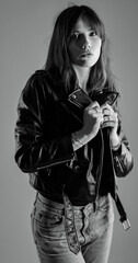 Monochrome studio portrait of a young woman wearing a leather jacket and jeans. This image is suitable for fashion beauty and style concepts.