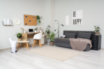 Blurred view of office with workplace, plants and sofa