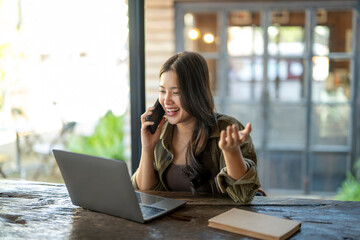 Asian woman remote working from cafe calling with smartphone