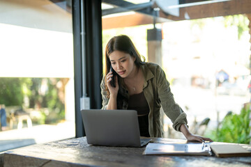 Young asian woman working remotely, talking on phone