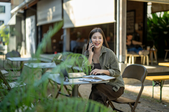 Young asian woman talking on phone working outdoor
