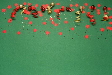 Red and gold confetti with Christmas balls on green background