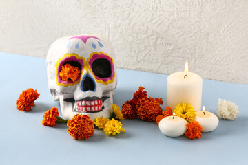 Painted skull with marigold flowers and candles on color background. Celebration of Mexico's Day of...
