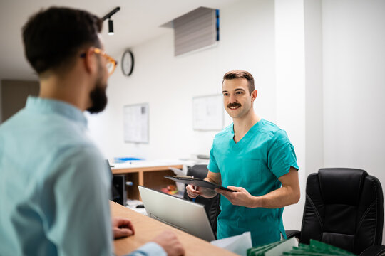 Medical receptionist checking in patient at clinic desk