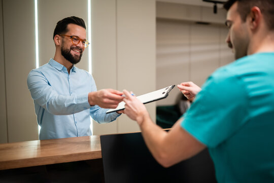 Patient signing medical form at clinic reception