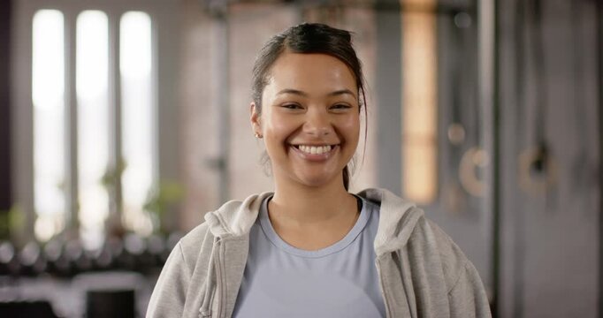 Woman shifting lips into subtle smile and widening grin in fitness studio with ropes weights