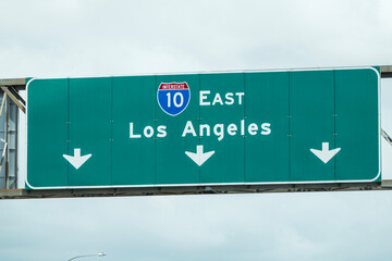 Los Angeles Interstate 10 east freeway arrow sign with gray cloudy sky.