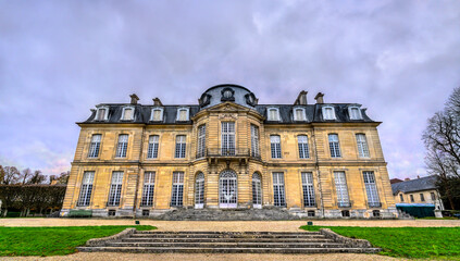 The historic Chateau de Champs-sur-Marne in the Paris region of France. The 18th-century French castle features classical architecture and symmetrical gardens under a cloudy sky