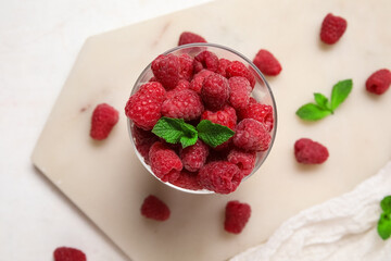 Glass with fresh raspberry and mint on light background, closeup