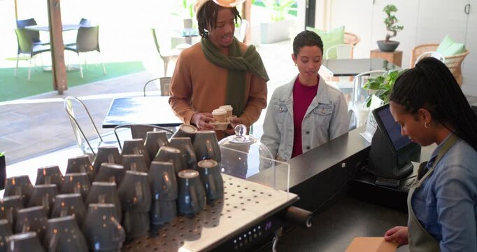 Diverse couple approaching counter, ordering pastry, barista processing payment, exiting with cups