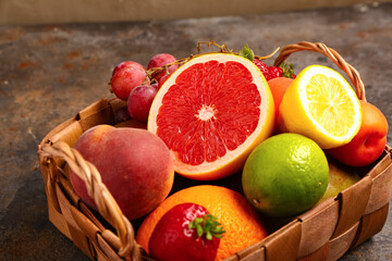 Wicker basket with different fresh fruits on dark table