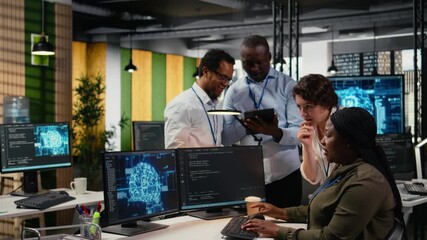 Multiethnic technicians use devices in AI startup office to train predictive models for language processing tasks. Multiracial coworkers use deep learning technical expertise for tasks, camera A