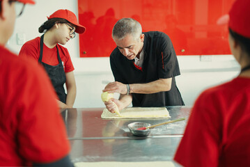 Chef teaching students pastry making techniques in a baking class