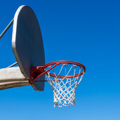 Outdoor basketball net under a clear blue sky.