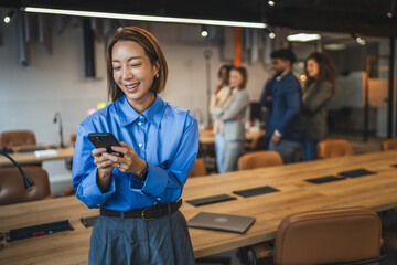 Professional woman smiling using smart phone in modern office