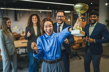 Diverse business team celebrating achievement receiving golden trophy award