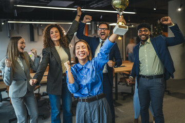 Diverse business team celebrating achievement receiving golden trophy award