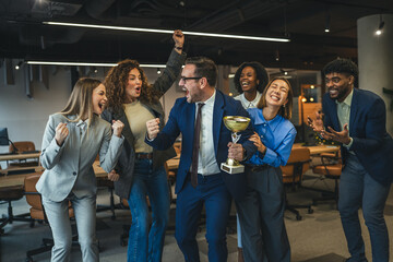Obraz premium Diverse business team celebrating achievement and success holding trophy