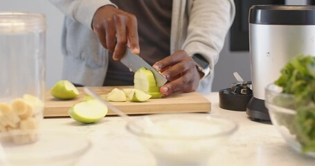 After grabbing green fruit on light colored counter, person is slicing wedges for blender smoothie - Powered by Adobe