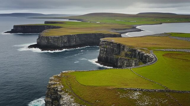 Breathtaking aerial view of the massive, jagged sea cliffs and vibrant green fields of the stunning Aran Islands.