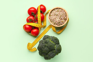 Obraz premium Fresh vegetables, bowl of seeds and yellow measuring tape on green background. Diet concept