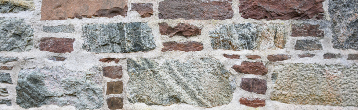 Hand cut stone natural stone block wall with rocks mortared together, as a rustic patterned background
