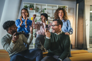Diverse coworkers playing video game together celebrating success