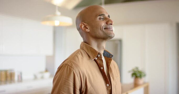Male looking upward in bright kitchen reacting to voice, smiling then laughing under pendants
