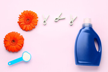 Laundry detergents, gerbera flowers and clothespins on pink background