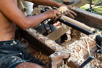 Traditional wood lathe turning process, close-up of artisan's hands creating detail.