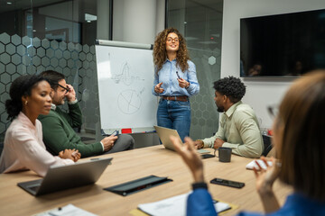 Businesswoman presenting data to diverse colleagues in meeting room