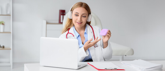 Female gynecologist with tampon box giving online consultation in clinic
