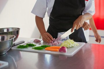Chef hands chopping fresh vegetables on white board