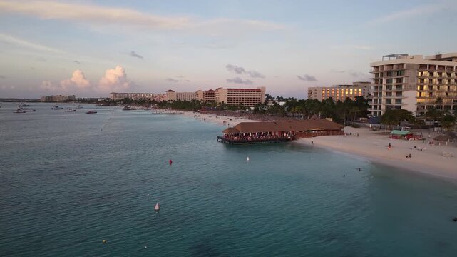 Video 4K 60FPS: Vuelo lateral en Palm Beach al atardecer, Aruba. Muelle e infraestructura.