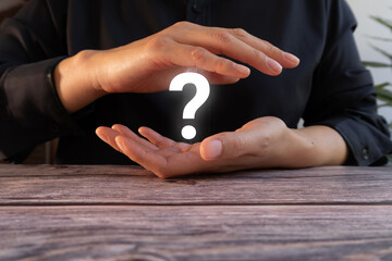 A person holding their hands in front of them with a question mark sign on the palm, representing making choices and reflecting on life's questions.