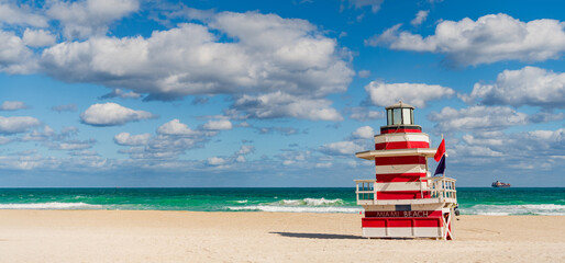 Lifeguard tower on the sandy Miami Beach shore. Iconic Art Deco lifeguard station under summer sky. Scenic view of South Beach coastline in Florida. Colorful lifeguard tower, symbol of Miami tourism.