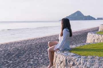 Woman Sitting on Beach and Watching Sunrise, Side View Silhouette with Ocean Horizon Background