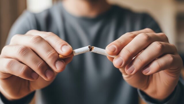 Person breaking cigarette in hands symbolizing quitting smoking and health choice