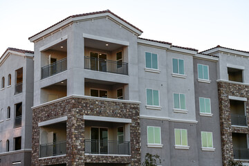 A modern multifamily apartment building with balconies, stone veneer accents, and completed exterior finishes, illustrating contemporary residential development and urban housing construction