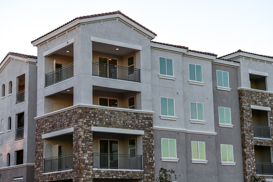 A modern multifamily apartment building with balconies, stone veneer accents, and completed exterior finishes, illustrating contemporary residential development and urban housing construction