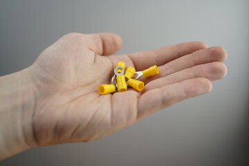 Hand Holding Multiple Yellow Ring Terminal Connectors
