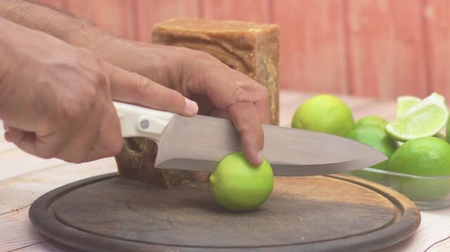 Close-up hands cut lemon together amber-colored block made from cooked and dried sugarcane juice is used to Venezuelan desserts and Papel&oacute;n con Lim&oacute;n drink