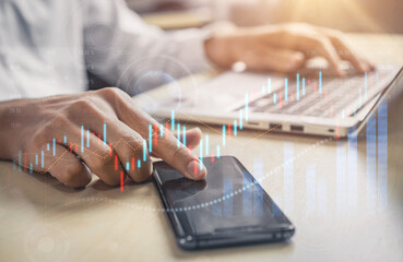 A business professional analyzes financial data using a smartphone and laptop. Rising stock charts emphasize market trends and investment opportunities in a modern workspace. Scalp