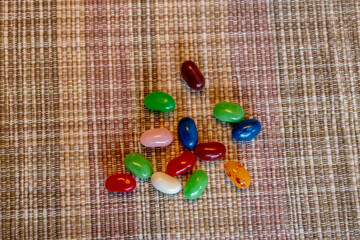 Close up top view texture background of colorful jellybeans randomly grouped on a woven placemat background