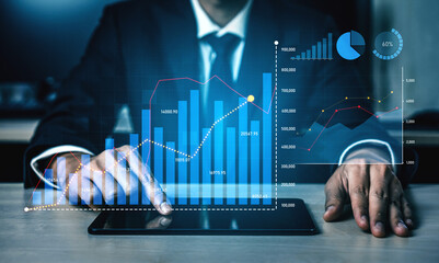 Businessman using a digital tablet to analyze financial data with modern graphs and charts in a professional office, symbolizing growth and strategic planning. Scalp